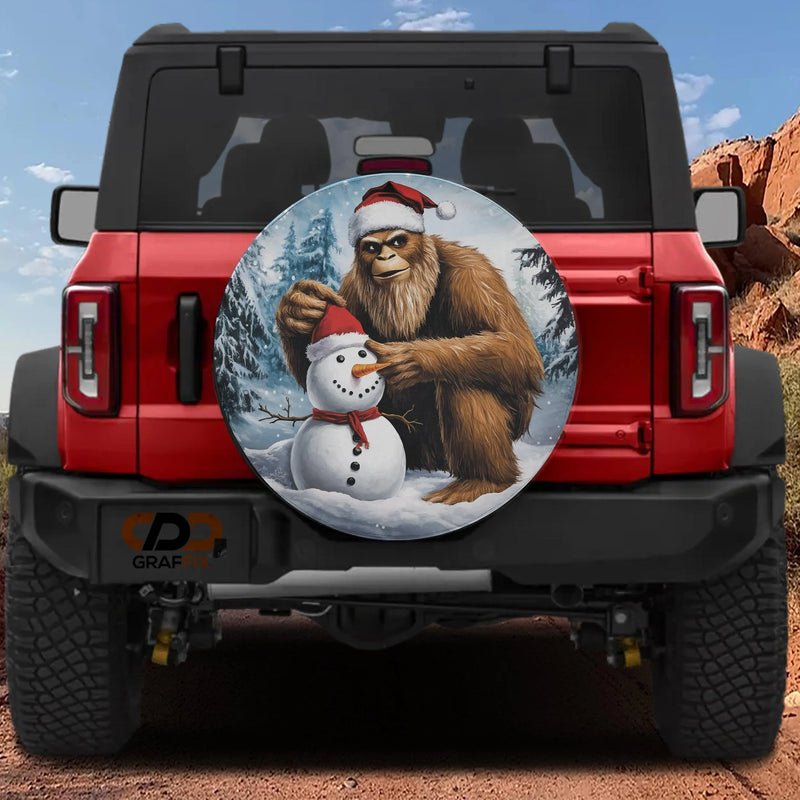 Sasquatch Holiday Tire Cover, Bigfoot Building Snowman Spare Tire Cover, Humorous Winter Scene Wheel Cover, Christmas Present for Bigfoot Fans